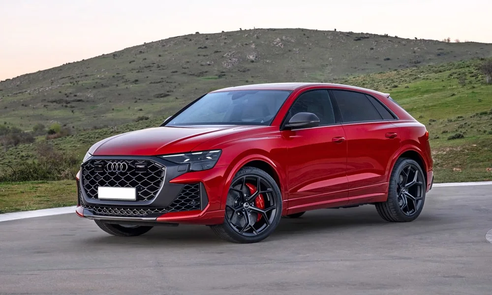 Фото Audi RS Q8 (2024) — вид спереди, фото 4. Передок в красном исполнении — крупная светотехника и выразительный бампер. Рисунок ходовых огней — подпись модели, по нему её узнают в потоке Audi RS Q8 (2024) — вид спереди, фото 4
