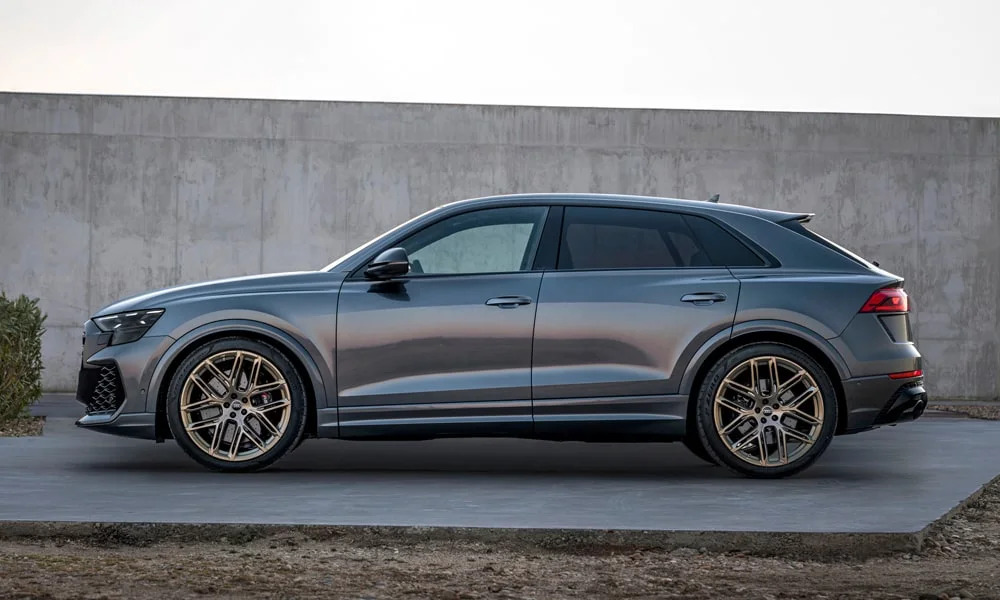 Фото Audi RS Q8 (2024) — вид сбоку. Серый кузов в профиль — пропорции, высота посадки и дизайн дисков. Хромированные или чёрные молдинги окон отличают комплектации Audi RS Q8 (2024) — вид сбоку
