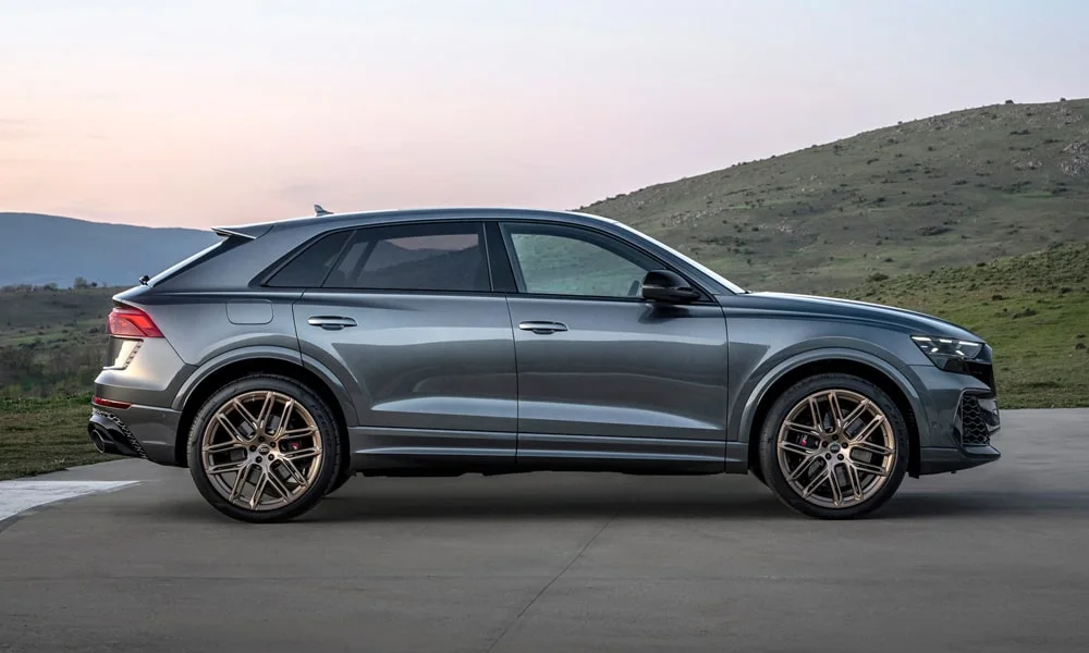 Фото Audi RS Q8 (2024) — вид сбоку, фото 2. Сбоку читаются линия остекления и характер выштамповок на сером кузове Audi RS Q8 (2024) — вид сбоку, фото 2