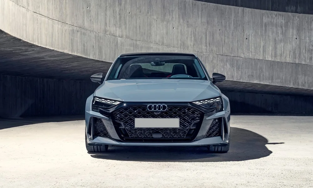 Фото Audi RS3 (2022) — вид спереди, фото 4. Серый кузов, строгая симметрия оптики — базовый ракурс знакомства с дизайном. Рисунок ходовых огней — подпись модели, по нему её узнают в потоке Audi RS3 (2022) — вид спереди, фото 4