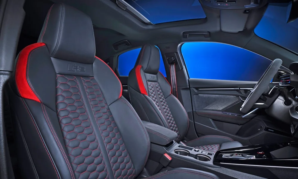 Фото Audi RS3 (2022) — интерьер. Общий план салона: посадка, материалы и организация пространства в красно-чёрной гамме. Уровень отделки читается по стыкам панелей и мягким поверхностям в зонах касания Audi RS3 (2022) — интерьер