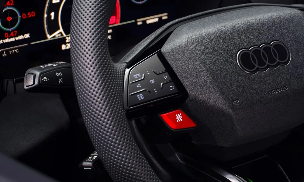 Фото Audi RS3 (2022) — руль. Обшивка обода и компоновка спиц крупным планом. Правильная посадка: руки на «9 и 3», приборы читаются поверх обода Audi RS3 (2022) — руль