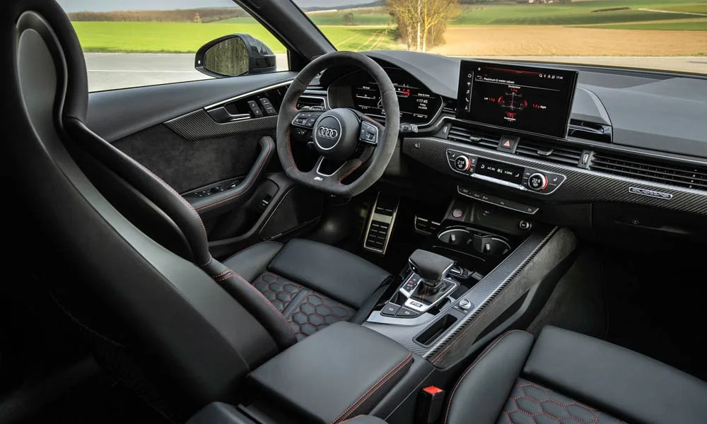 Фото Audi RS4 Avant — интерьер. Салон в тёмной отделке: архитектура передней панели, консоль и кресла. Светлая гамма зрительно расширяет салон, тёмная — практичнее в уходе Audi RS4 Avant — интерьер