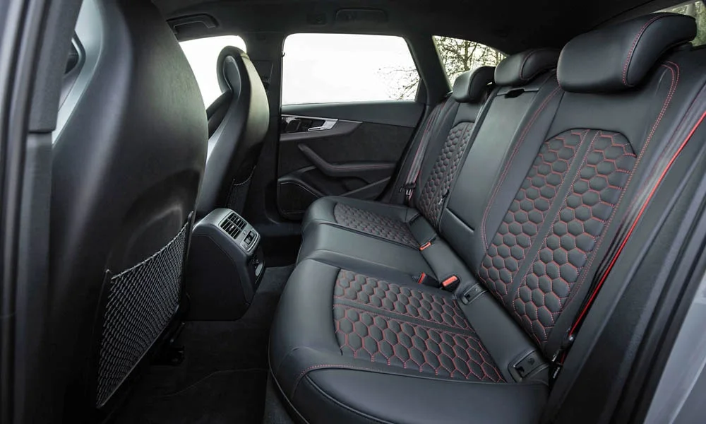 Фото Audi RS4 Avant — задние сиденья. Посадка второго ряда: подголовники и подлокотник. Плоский пол упрощает посадку втроём Audi RS4 Avant — задние сиденья