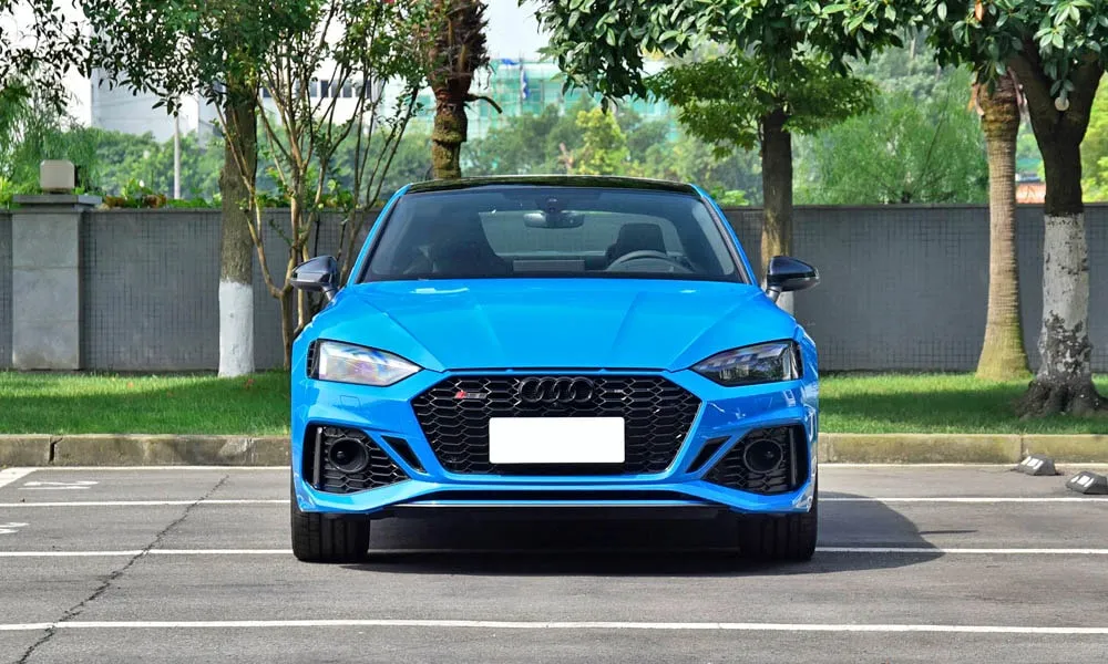 Фото Audi RS5 — вид спереди, фото 3. Синий кузов, строгая симметрия оптики — базовый ракурс знакомства с дизайном. Рисунок ходовых огней — подпись модели, по нему её узнают в потоке Audi RS5 — вид спереди, фото 3