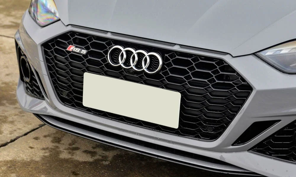 Фото Audi RS5 — решётка радиатора. Рисунок решётки: сетка, ламели или глухая панель у электроверсий. Активные жалюзи за решёткой закрываются на трассе ради аэродинамики — есть у ряда моделей Audi RS5 — решётка радиатора