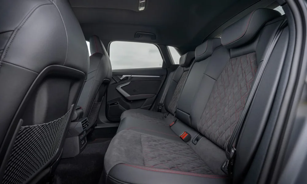 Фото Audi S3 Sportback (2024) — задние сиденья. Задний диван в алькантаре: посадка и центральный подлокотник. Спинки складываются под длинные грузы у большинства версий Audi S3 Sportback (2024) — задние сиденья