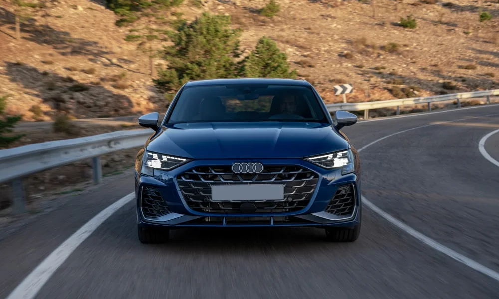 Фото Audi S3 (2024) — вид спереди, фото 6. Передок в синем исполнении — крупная светотехника и выразительный бампер. Рисунок ходовых огней — подпись модели, по нему её узнают в потоке Audi S3 (2024) — вид спереди, фото 6
