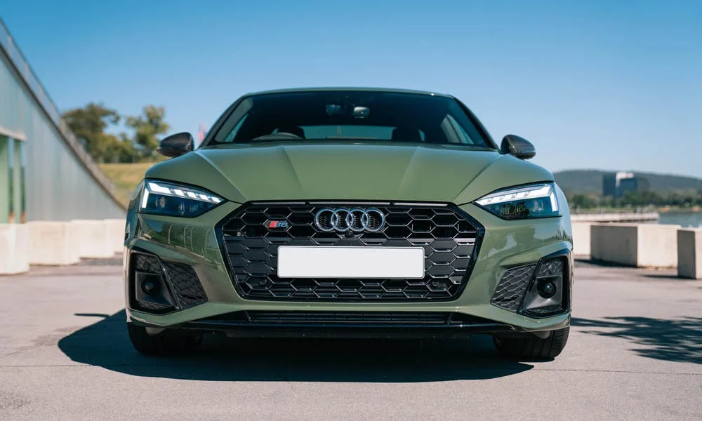 Фото Audi S5 (2024) — вид спереди, фото 17. Передок в зелёном исполнении — крупная светотехника и выразительный бампер. Рисунок ходовых огней — подпись модели, по нему её узнают в потоке Audi S5 (2024) — вид спереди, фото 17
