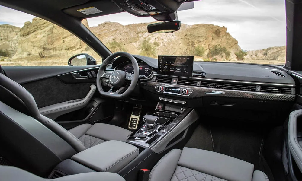 Фото Audi S5 (2024) — интерьер, фото 7. Общий план салона: архитектура панели, консоль и кресла. Светлая гамма зрительно расширяет салон, тёмная — практичнее в уходе Audi S5 (2024) — интерьер, фото 7