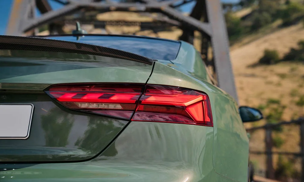 Фото Audi S5 (2024) — вид сзади, фото 14. Линия крыши, стойки и задняя дверь в зелёном исполнении. Насадки выхлопа или их имитация внизу бампера различают версии Audi S5 (2024) — вид сзади, фото 14