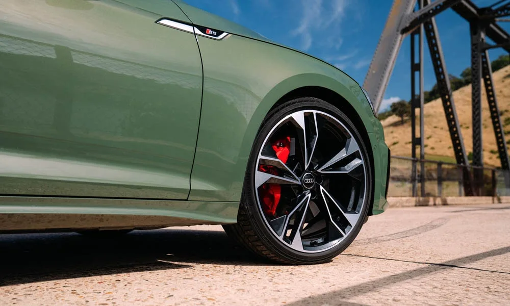Фото Audi S5 (2024) — вид сбоку, фото 3. Сбоку читаются линия остекления и характер выштамповок на зелёном кузове. Длинная база — простор второго ряда; короткие свесы упрощают парковку Audi S5 (2024) — вид сбоку, фото 3
