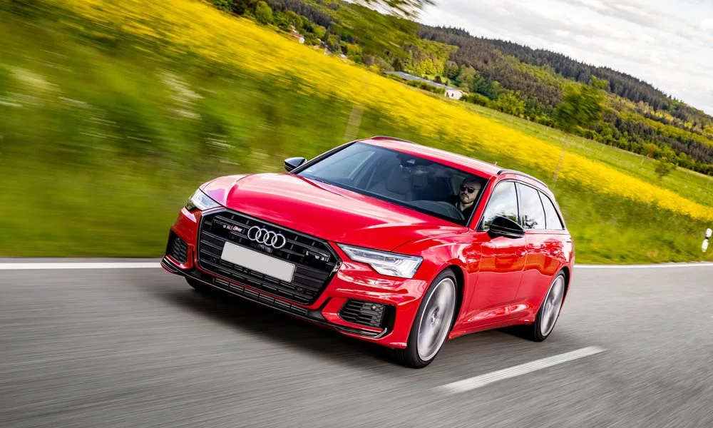 Фото Audi S6 Avant (2024) — вид спереди, фото 12. Красный кузов, строгая симметрия оптики — базовый ракурс знакомства с дизайном. Дневные ходовые огни включаются автоматически с запуском Audi S6 Avant (2024) — вид спереди, фото 12