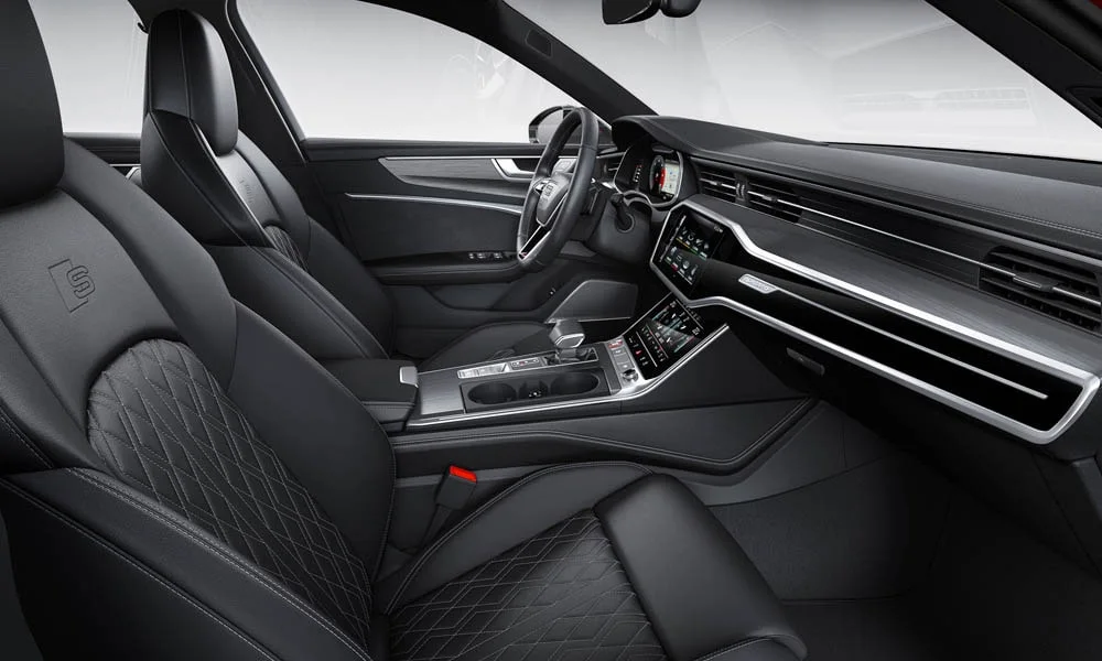 Фото Audi S6 Avant (2024) — интерьер. Общий план салона: посадка, материалы и организация пространства в тёмной гамме. Уровень отделки читается по стыкам панелей и мягким поверхностям в зонах касания Audi S6 Avant (2024) — интерьер