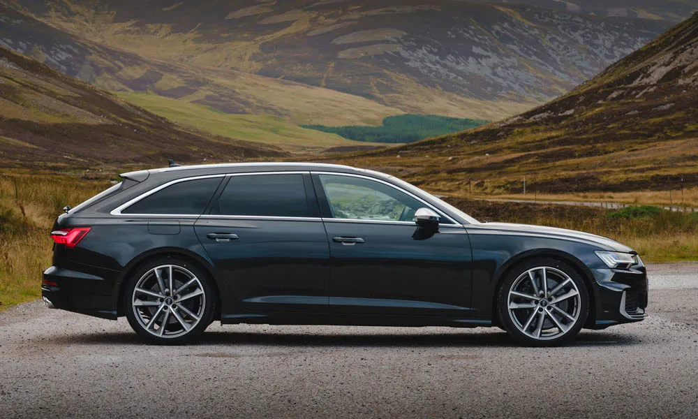Фото Audi S6 Avant (2024) — вид сбоку. Профиль в чёрном цвете: соотношение колёсной базы и свесов. Хромированные или чёрные молдинги окон отличают комплектации Audi S6 Avant (2024) — вид сбоку