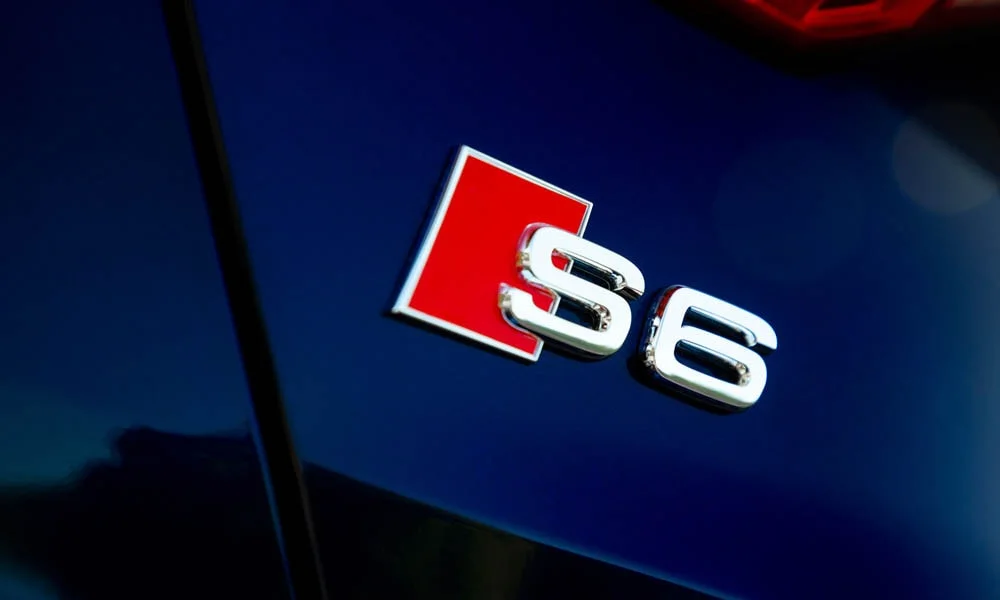 Фото Audi S6 — эмблема. Логотип марки крупным планом. Шильдик версии на корме помогает отличать комплектации Audi S6 — эмблема