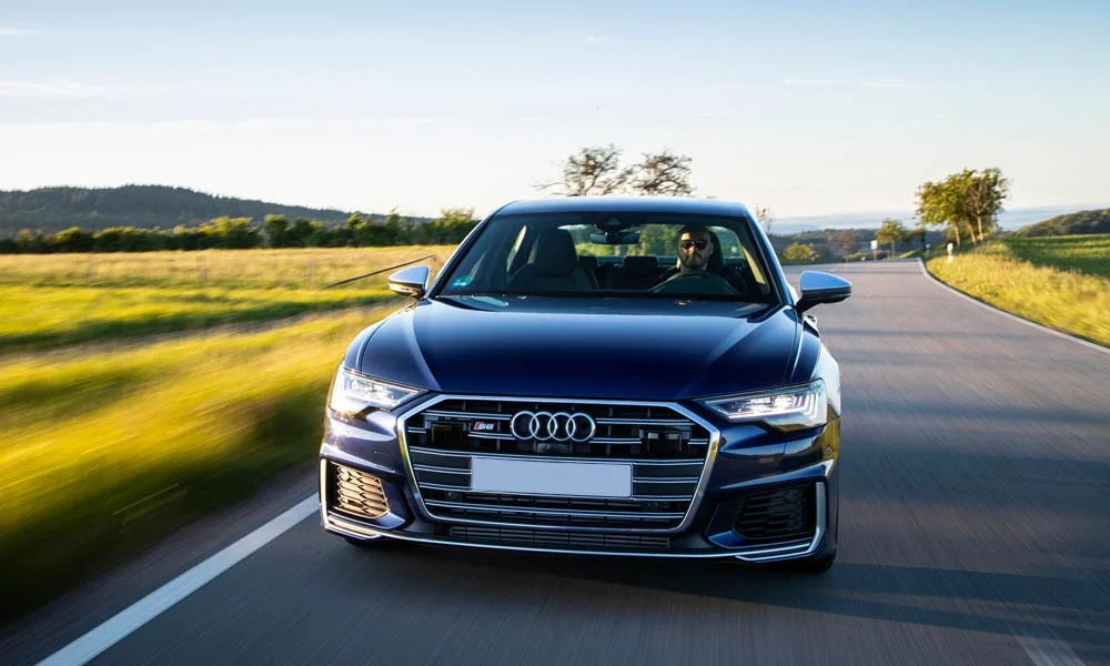 Фото Audi S6 — вид спереди, фото 3. Кузов в синем цвете: рисунок оптики и решётки задаёт узнаваемое «лицо» модели. Рисунок ходовых огней — подпись модели, по нему её узнают в потоке Audi S6 — вид спереди, фото 3