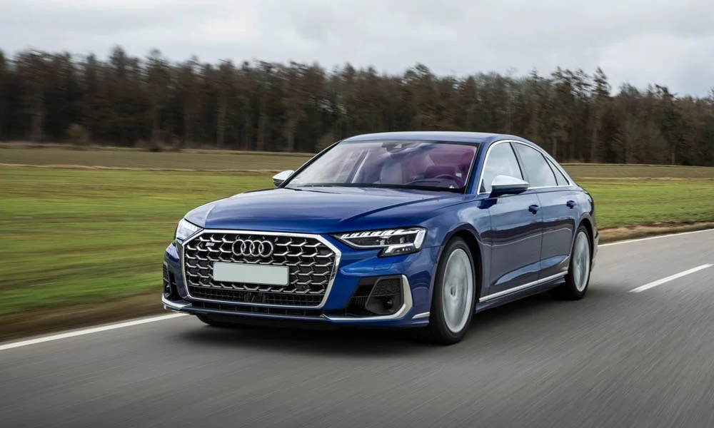 Фото Audi S8 (2024) — вид спереди, фото 5. Передок в синем исполнении — крупная светотехника и выразительный бампер. Рисунок ходовых огней — подпись модели, по нему её узнают в потоке Audi S8 (2024) — вид спереди, фото 5