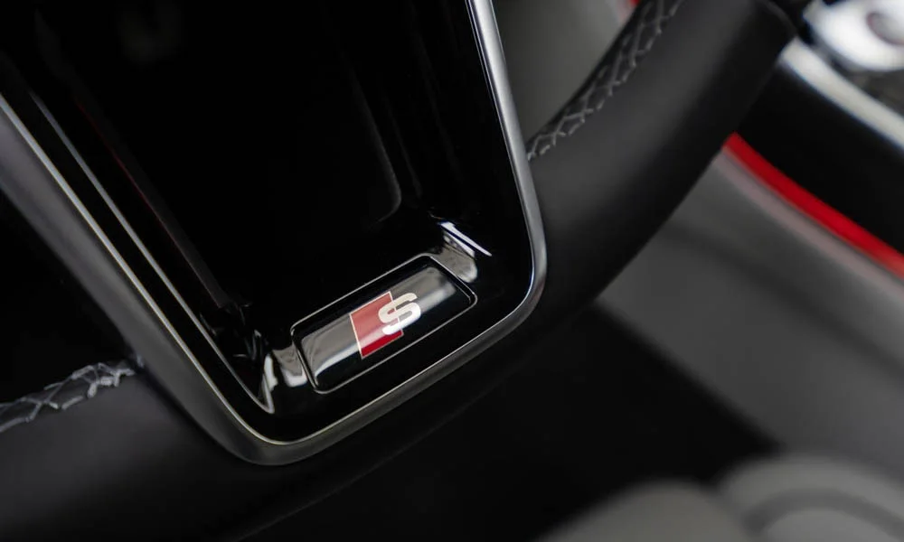 Фото Audi S8 (2024) — руль. Обшивка обода и компоновка спиц крупным планом. Правильная посадка: руки на «9 и 3», приборы читаются поверх обода Audi S8 (2024) — руль