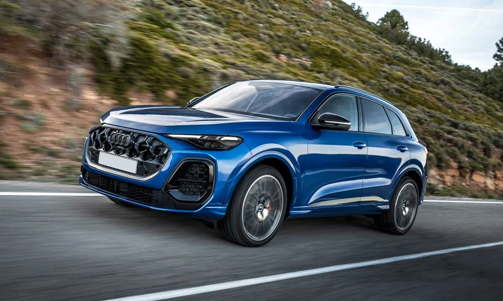 Фото Audi SQ5 (2024) — вид спереди, фото 7. Передок в синем исполнении — крупная светотехника и выразительный бампер. Рисунок ходовых огней — подпись модели, по нему её узнают в потоке Audi SQ5 (2024) — вид спереди, фото 7