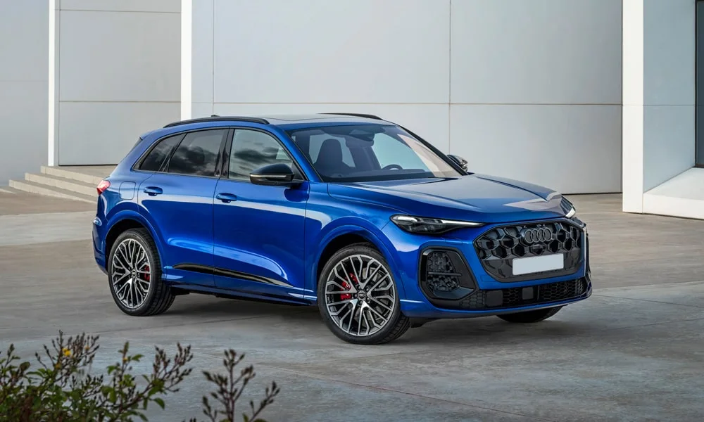 Фото Audi SQ5 (2024) — вид спереди, фото 8. Передок в синем исполнении — крупная светотехника и выразительный бампер. Рисунок ходовых огней — подпись модели, по нему её узнают в потоке Audi SQ5 (2024) — вид спереди, фото 8