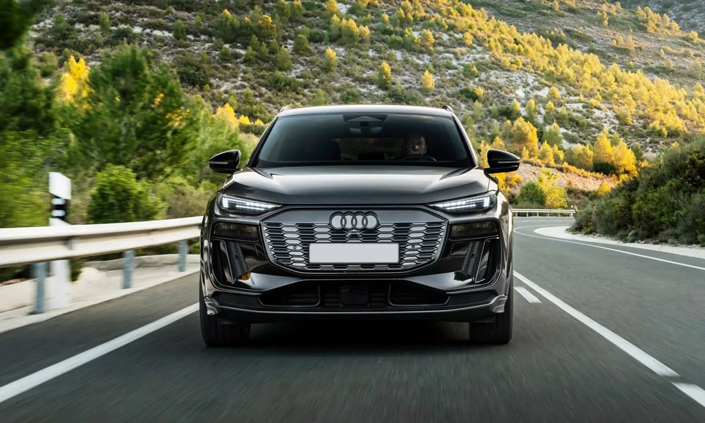 Фото Audi SQ6 e-tron (2024) — вид спереди, фото 7. Чёрный кузов, строгая симметрия оптики — базовый ракурс знакомства с дизайном. Дневные ходовые огни включаются автоматически с запуском Audi SQ6 e-tron (2024) — вид спереди, фото 7