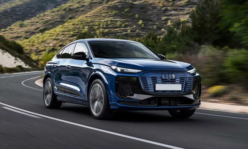 Фото Audi SQ6 Sportback e-tron (2024) — вид спереди, фото 6. Синий кузов, строгая симметрия оптики — базовый ракурс знакомства с дизайном. Дневные ходовые огни включаются автоматически с запуском Audi SQ6 Sportback e-tron (2024) — вид спереди, фото 6