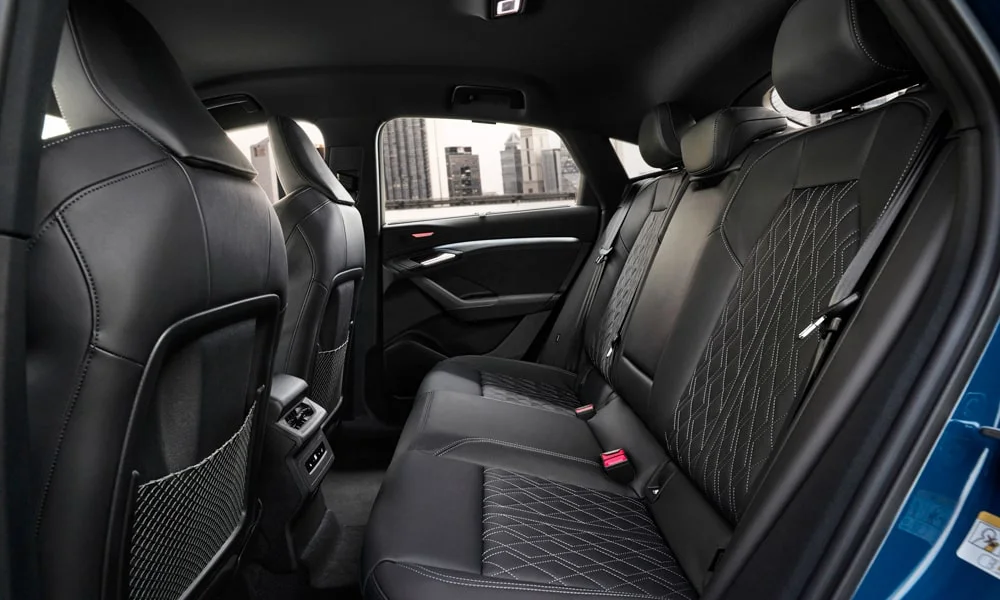 Фото Audi SQ6 Sportback e-tron (2024) — задние сиденья. Посадка второго ряда: подголовники и подлокотник. Спинки складываются под длинные грузы у большинства версий Audi SQ6 Sportback e-tron (2024) — задние сиденья