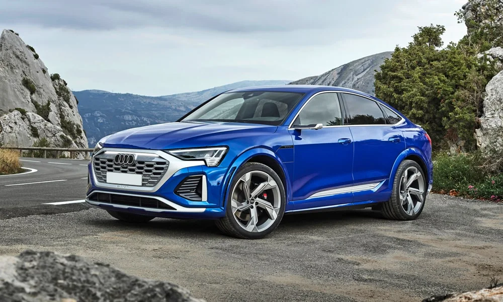 Фото Audi SQ8 Sportback e-tron (2024) — вид спереди, фото 7. Передок в синем исполнении — крупная светотехника и выразительный бампер. Рисунок ходовых огней — подпись модели, по нему её узнают в потоке Audi SQ8 Sportback e-tron (2024) — вид спереди, фото 7