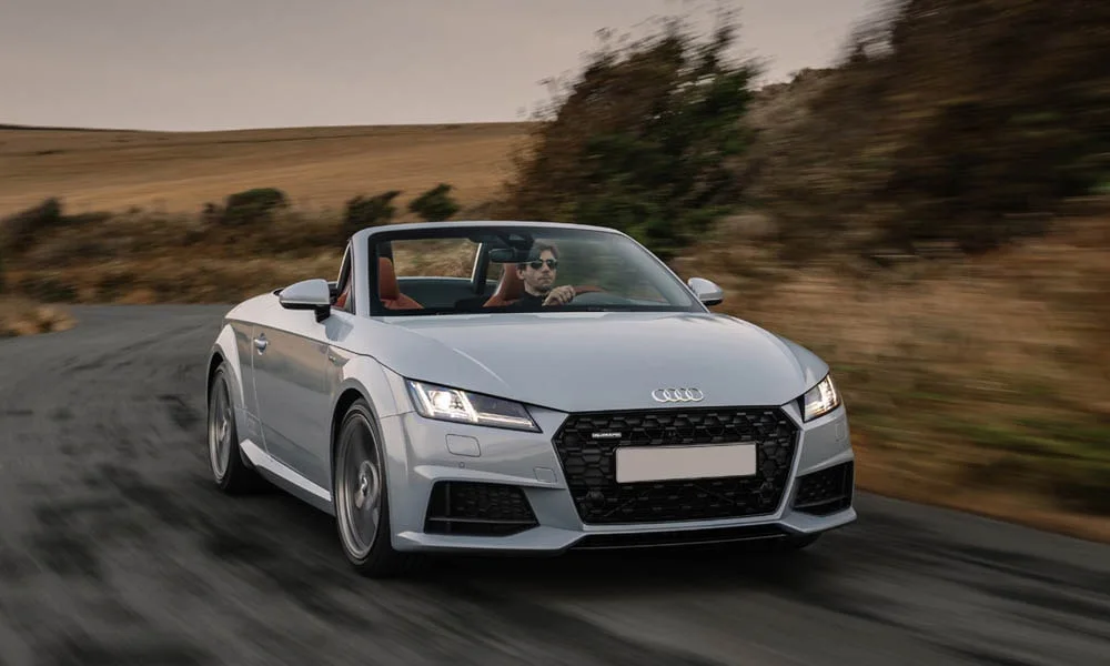 Фото Audi TT — вид спереди, фото 21. Передок в серебристом исполнении — крупная светотехника и выразительный бампер. Рисунок ходовых огней — подпись модели, по нему её узнают в потоке Audi TT — вид спереди, фото 21