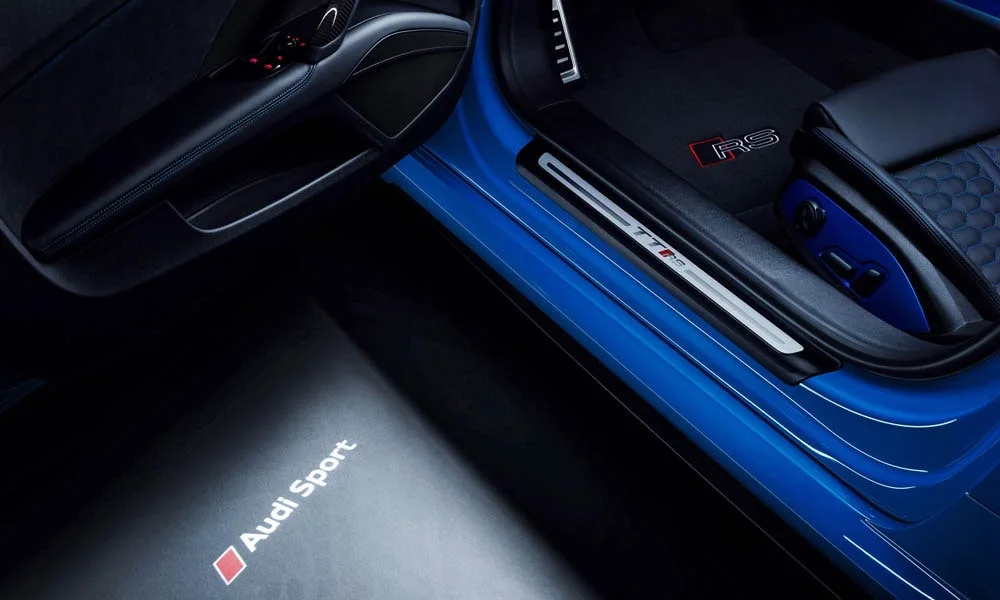 Фото Audi TT RS — дверная карта, фото 3. Дверная карта в тёмно-синей отделке: подлокотник, динамик и блок стеклоподъёмников. Решётка динамика в двери — часть штатной акустики Audi TT RS — дверная карта, фото 3