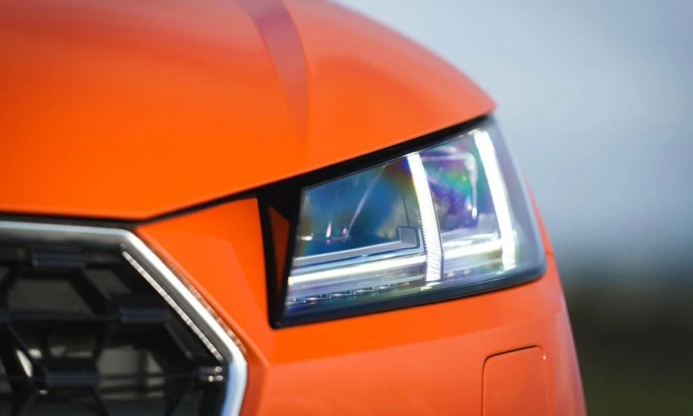 Фото Audi TT — вид спереди, фото 6. Передок в оранжевом исполнении — крупная светотехника и выразительный бампер. Рисунок ходовых огней — подпись модели, по нему её узнают в потоке Audi TT — вид спереди, фото 6