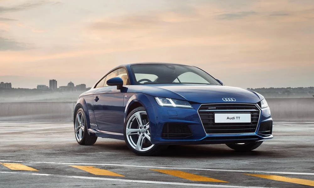 Фото Audi TT — вид спереди, фото 8. Синий кузов, строгая симметрия оптики — базовый ракурс знакомства с дизайном. Дневные ходовые огни включаются автоматически с запуском Audi TT — вид спереди, фото 8