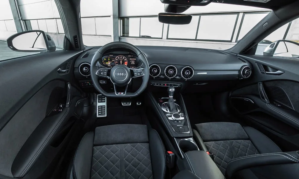 Фото Audi TT — интерьер, фото 3. Интерьер с тёмной отделкой — видно сочетание материалов панели и кресел. Светлая гамма зрительно расширяет салон, тёмная — практичнее в уходе Audi TT — интерьер, фото 3