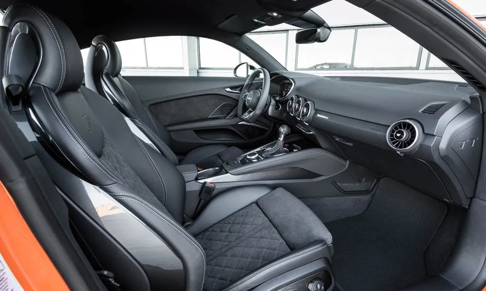 Фото Audi TT — интерьер, фото 4. Интерьер с тёмной отделкой — видно сочетание материалов панели и кресел. Светлая гамма зрительно расширяет салон, тёмная — практичнее в уходе Audi TT — интерьер, фото 4