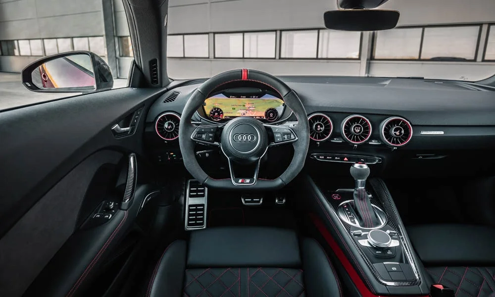Фото Audi TT — руль. Обшивка обода и компоновка спиц крупным планом. Клавиши на спицах управляют медиа, круизом и ассистентами — руки остаются на руле Audi TT — руль