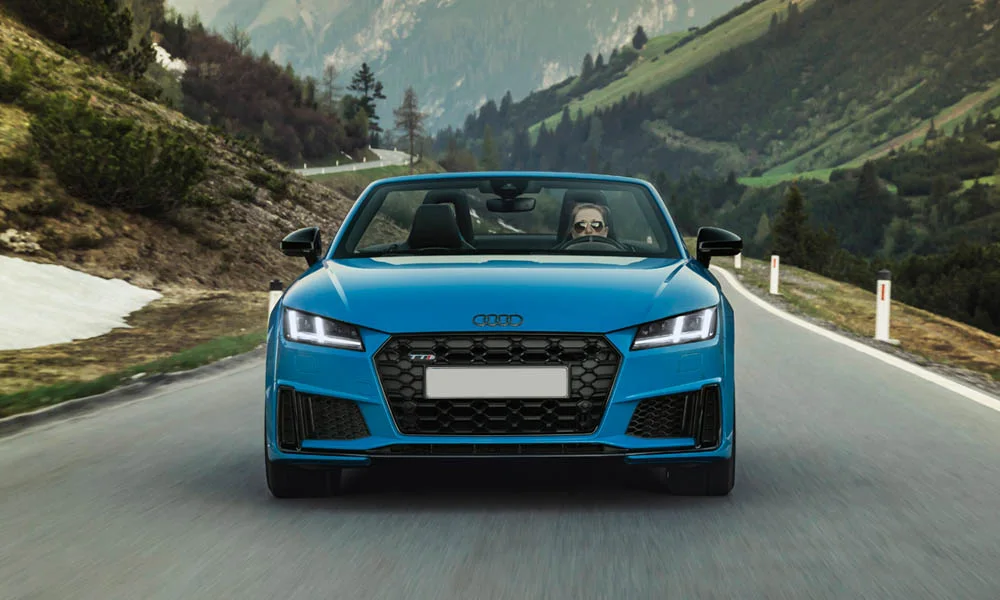 Фото Audi TTS — вид спереди, фото 20. Синий кузов, строгая симметрия оптики — базовый ракурс знакомства с дизайном. Рисунок ходовых огней — подпись модели, по нему её узнают в потоке Audi TTS — вид спереди, фото 20