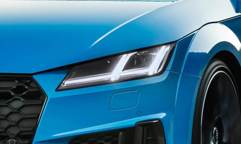 Фото Audi TTS — вид спереди, фото 22. Синий кузов, строгая симметрия оптики — базовый ракурс знакомства с дизайном. Дневные ходовые огни включаются автоматически с запуском Audi TTS — вид спереди, фото 22