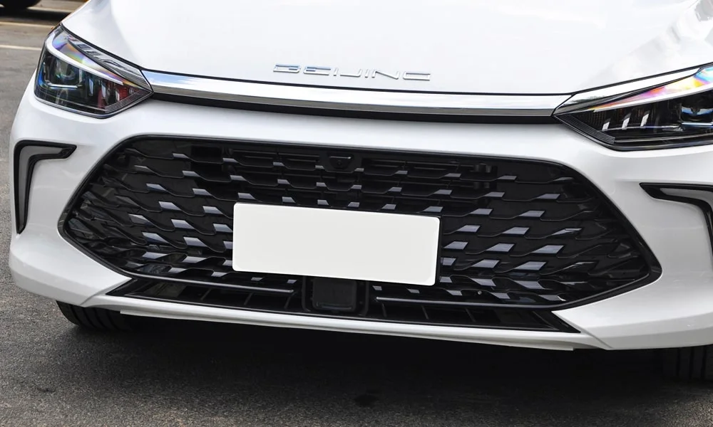 Фото BAIC U5 Plus (2023) — решётка радиатора. Фирменный рисунок облицовки — визитная карточка марки. За решёткой у многих комплектаций стоит радар адаптивного круиз-контроля BAIC U5 Plus (2023) — решётка радиатора