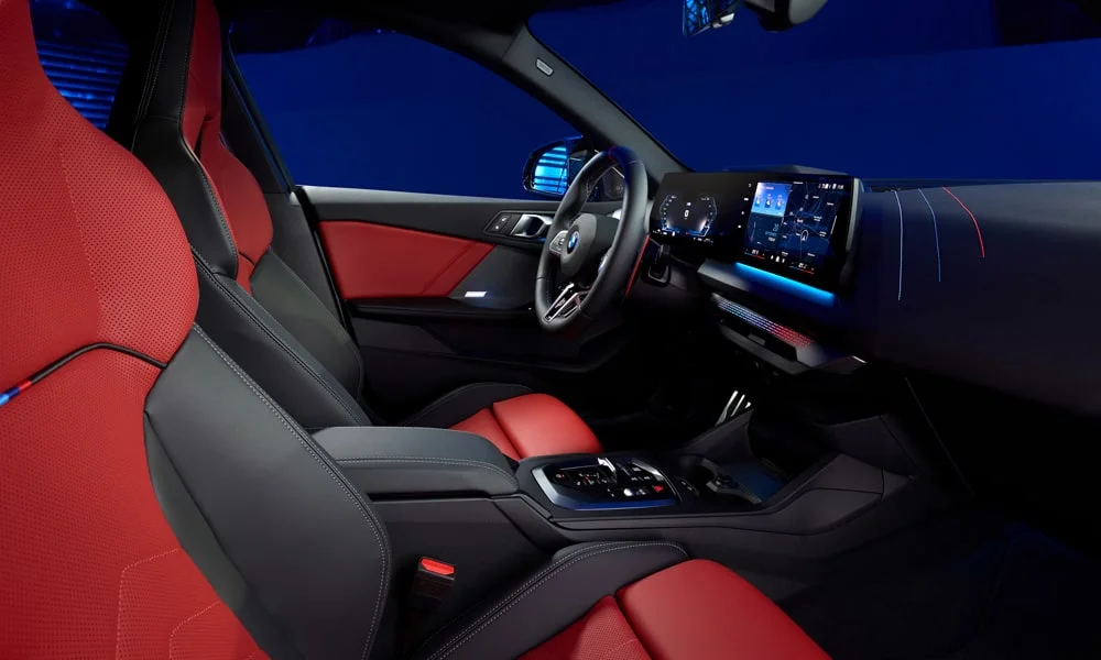Фото BMW 2 серии Gran Coupe (2024) — интерьер. Общий план салона: посадка, материалы и организация пространства в красно-чёрной гамме. Светлая гамма зрительно расширяет салон, тёмная — практичнее в уходе BMW 2 серии Gran Coupe (2024) — интерьер