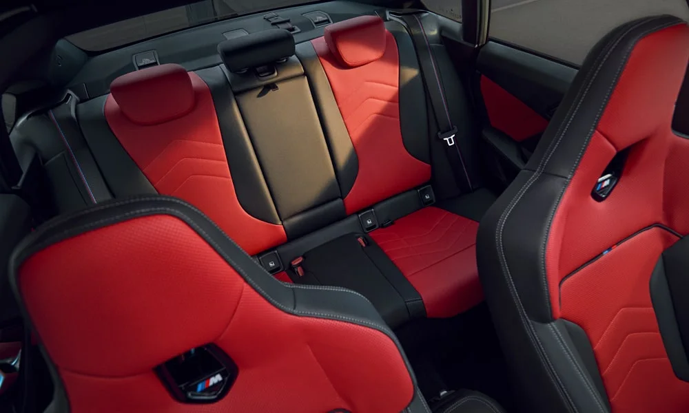 Фото BMW 2 серии Gran Coupe (2024) — задние сиденья. Второй ряд: профиль дивана, подголовники и обивка из перфорированной коже. Спинки складываются под длинные грузы у большинства версий BMW 2 серии Gran Coupe (2024) — задние сиденья