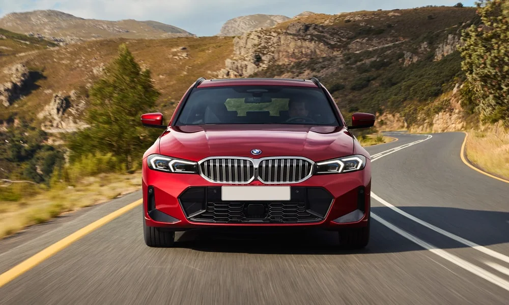 Фото BMW 3 серии Touring (2024) — вид спереди, фото 10. Красный кузов, строгая симметрия оптики — базовый ракурс знакомства с дизайном. Дневные ходовые огни включаются автоматически с запуском BMW 3 серии Touring (2024) — вид спереди, фото 10