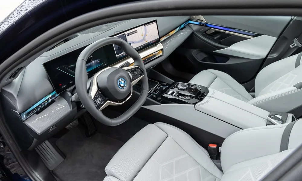Фото BMW i5 Touring — передняя панель. Компоновка экранов, дефлекторов и консоли. Мягкие материалы верхнего яруса и вставки задают уровень интерьера BMW i5 Touring — передняя панель