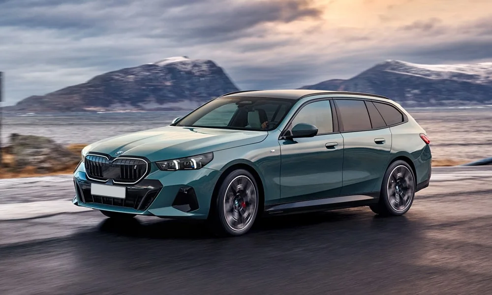 Фото BMW i5 Touring — вид спереди, фото 7. Кузов в зелёном цвете: рисунок оптики и решётки задаёт узнаваемое «лицо» модели. Рисунок ходовых огней — подпись модели, по нему её узнают в потоке BMW i5 Touring — вид спереди, фото 7