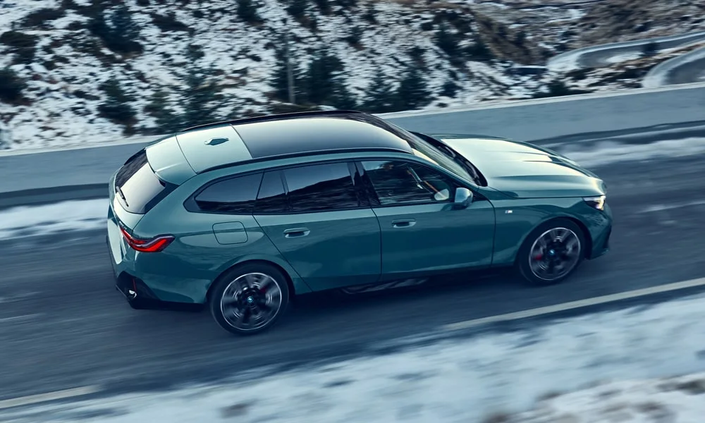 Фото BMW i5 Touring — крыша. Линия крыши и панорамное остекление с высоты. Рейлинги рассчитаны на поперечины для бокса или велокреплений BMW i5 Touring — крыша