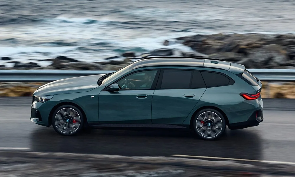 Фото BMW i5 Touring — вид сбоку. Сбоку читаются линия остекления и характер выштамповок на зелёном кузове. Длинная база — простор второго ряда; короткие свесы упрощают парковку BMW i5 Touring — вид сбоку