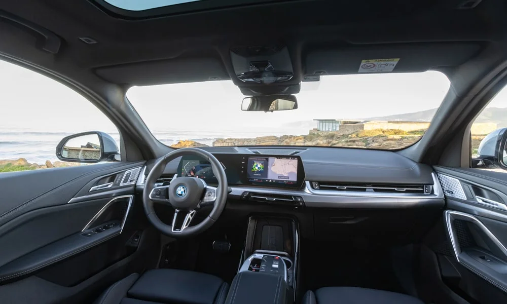 Фото BMW iX2 — передняя панель. Компоновка экранов, дефлекторов и консоли. Мягкие материалы верхнего яруса и вставки задают уровень интерьера BMW iX2 — передняя панель