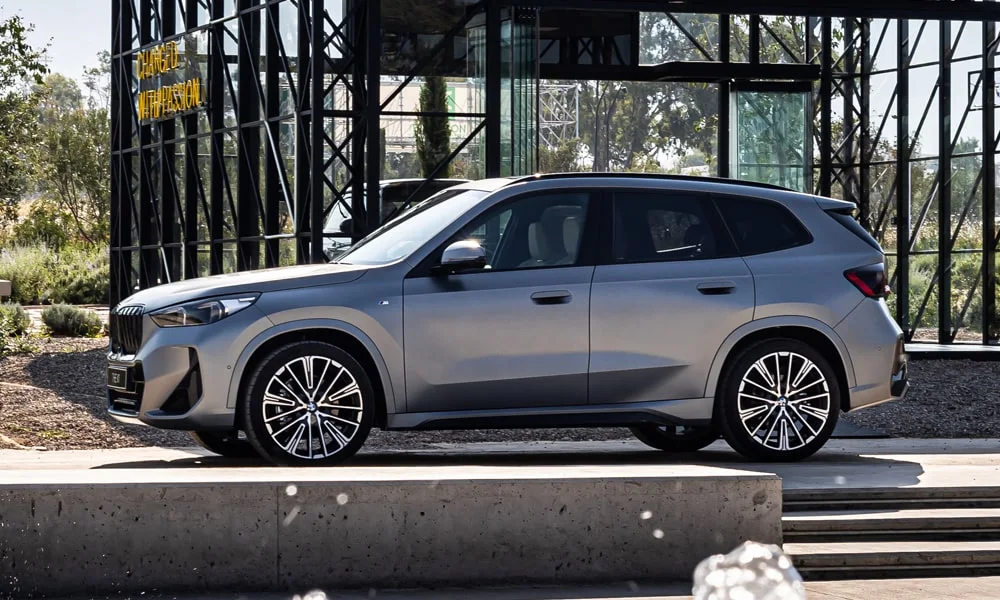 Фото BMW X1 (2024) — вид сбоку, фото 3. Профиль кузова: колёсная база, свесы и линия остекления. Хромированные или чёрные молдинги окон отличают комплектации BMW X1 (2024) — вид сбоку, фото 3