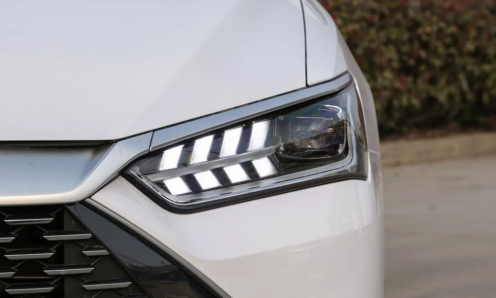 Фото BYD Qin Plus (2024) — вид спереди, фото 4. Передок в белом исполнении — крупная светотехника и выразительный бампер. Рисунок ходовых огней — подпись модели, по нему её узнают в потоке BYD Qin Plus (2024) — вид спереди, фото 4