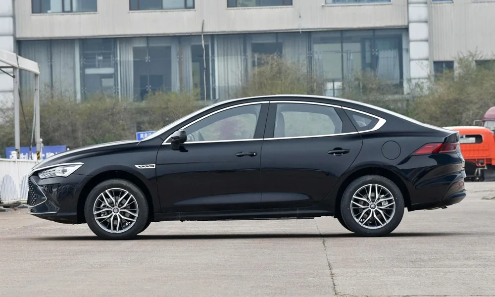 Фото BYD Qin Plus (2024) — вид сбоку, фото 4. Сбоку читаются линия остекления и характер выштамповок на чёрном кузове BYD Qin Plus (2024) — вид сбоку, фото 4